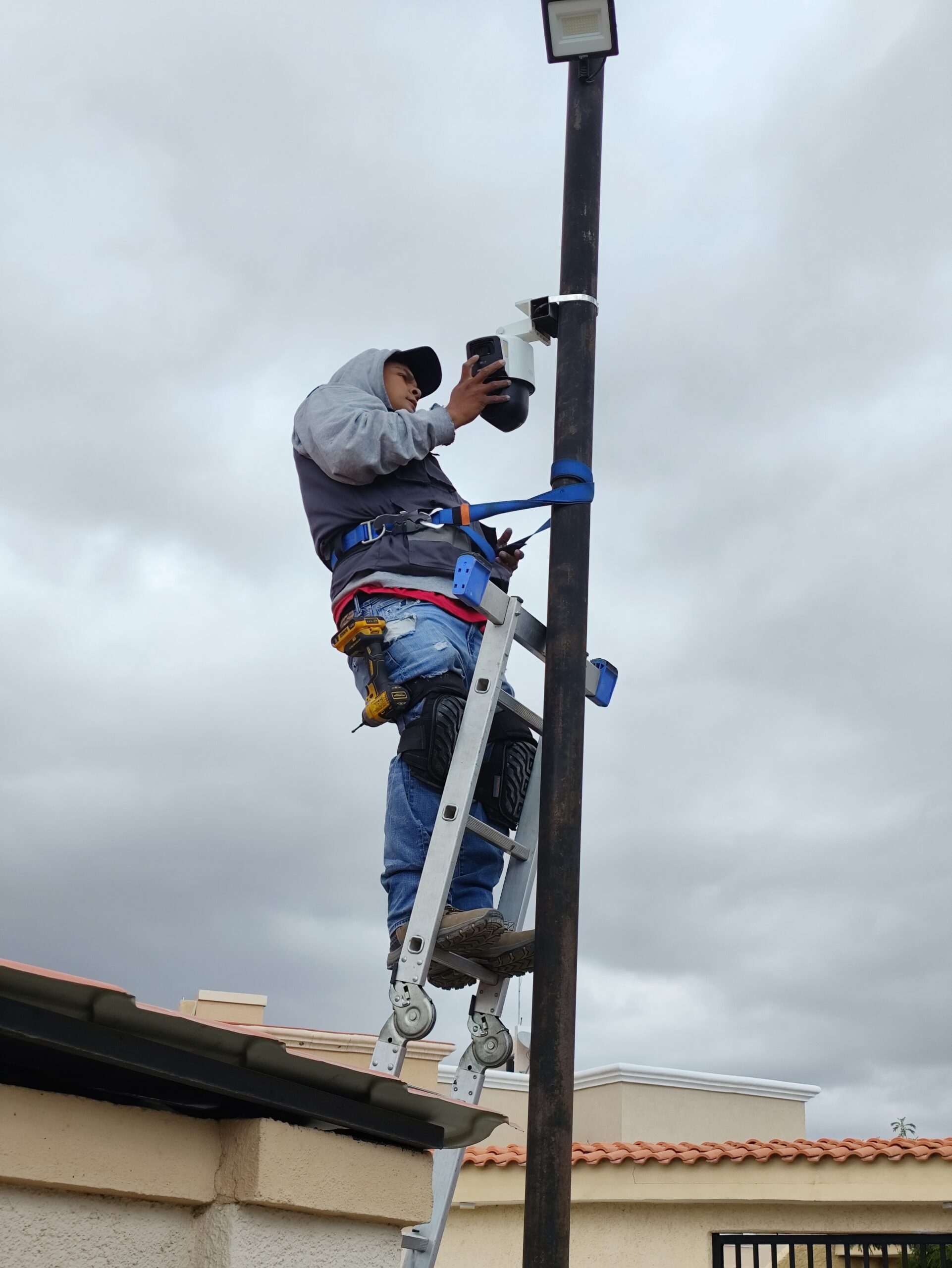 Técnico instalando una cámara de videovigilancia desde una escalera